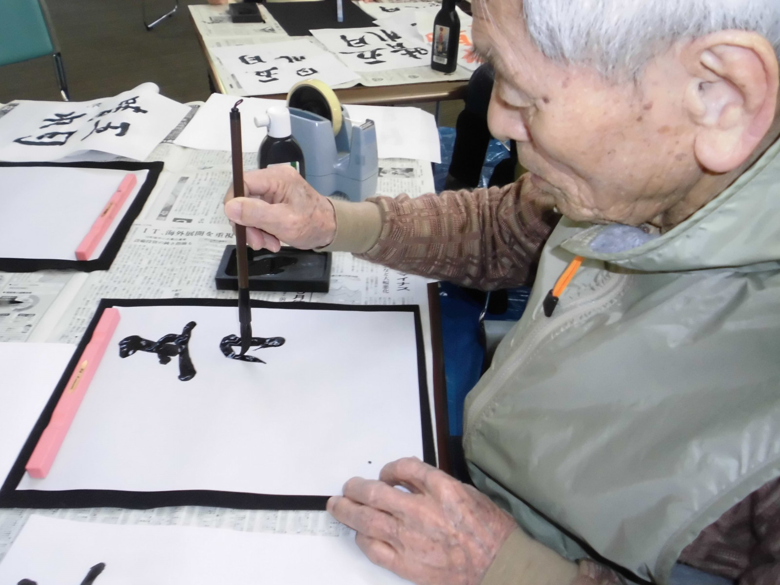 高齢入居者が書道・毛筆による創作活動を行っている様子。レクリエーション風景。