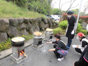 入居者が屋外で火を囲んで行事に参加している風景